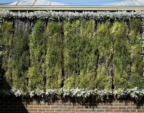 Painel de jardim vertical instalado em parede de tijolos, com plantas cobrindo toda a superfície